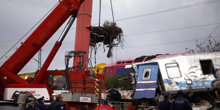 A crane removes debris of a train after a collision in Tempe, about 376 kilometres (235 miles) north of Athens, near Larissa city, Greece, Wednesday, March 1, 2023. Rescuers searched Wednesday through the burned-out wreckage of two trains that slammed into each other in northern Greece, killing and injured dozens of passengers. (AP Photo/Giannis Papanikos)